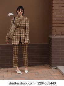 Street style fascion. Fashion & Style. Girl in a beige jacket and trousers on a beige brick background.