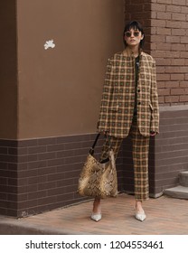 Street style fascion. Fashion & Style. Girl in a beige jacket and trousers on a beige brick background.