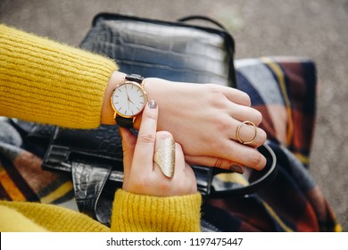 street style fashion details. close up, young fashion blogger wearing a sweater and a analog wrist watch. stylish woman checking the time on her watch. autumn/fall season.
