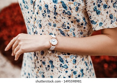 Street style, fashion, trendy summer woman`s outfit, details concept: white elegant wrist watch on hand with reptile textured leather strap, blue floral print dress - Powered by Shutterstock