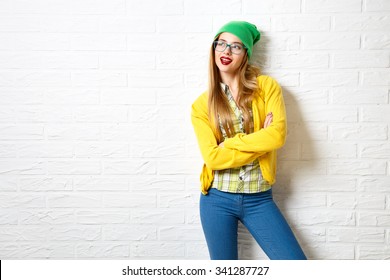 Street Style Hipster Girl At White Brick Wall Background. Trendy Casual Fashion Outfit In Winter. Copy Space.