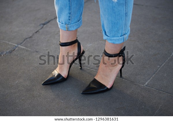 Street\
style image of stylish woman wearing pointed toe stilettos and\
casual fit pale denim jeans, close up,\
horizontal