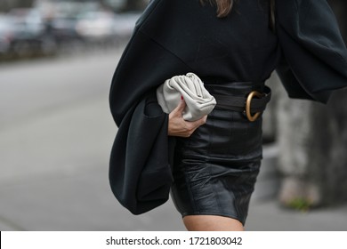 Street style outfit – Woman wearing a black oversized sweater and leather skirt matched with a clutch bag – StreetStyleFW2020