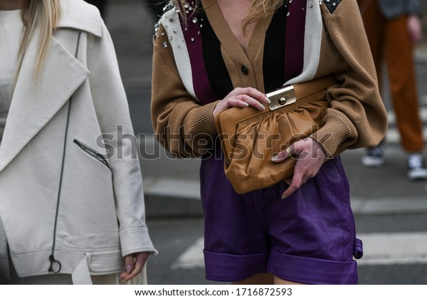 Street style outfit – Woman wearing a\
striped knitted cardigan, purple synthetic leather pants and a\
brown handbag -\
StreetStyleFW2020