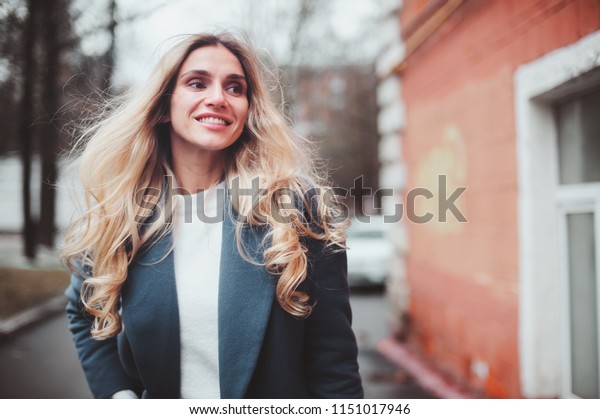 street style portrait of young woman walking\
in city in autumn or winter in warm\
coat
