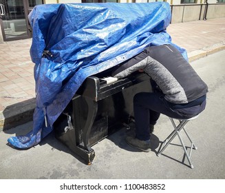 Street of the summer city. On the road is a piano. The piano is covered with a blanket. The man is sleeping on the keys. Photographed in Ukraine, Kiev. Horizontal frame. Color image - Powered by Shutterstock