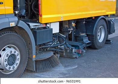 Street sweeper cleans street with brushes and water