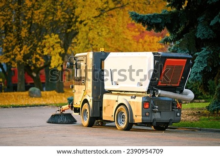 Street sweeper machine cleaning street from fallen leaves and dust, vacuum cleaner. Vehicle sweeping streets, cleaning up sidewalk. Road sweeper