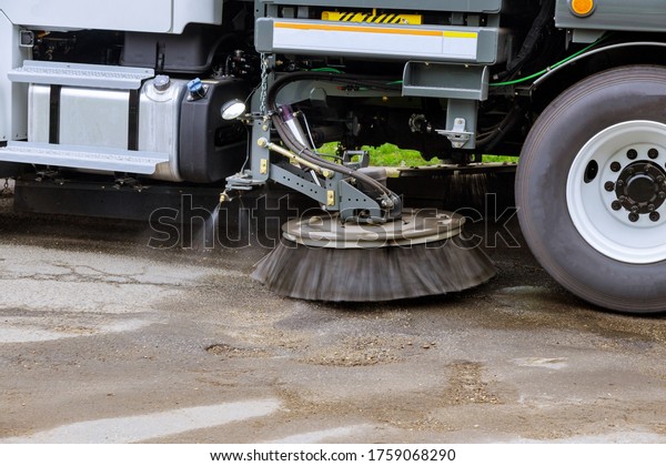 Street sweeper machine cleaning the streets in\
utility service on the\
town.