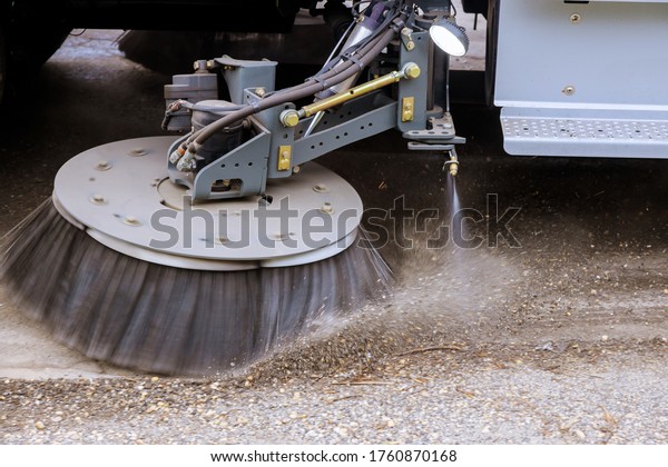 Street sweeper machine cleaning the streets in\
utility service on the\
town.
