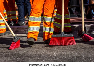Street sweepers with broom and typical orange uniform Brazilian