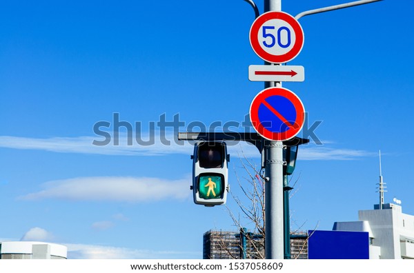 Street traffic light at\
pedestrain crossing crosswalk sign with against blue sky background\
close up.