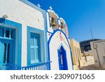 Street view of Manolas village with  brightly painted Orthodox churches and historic cave housesat the picture-Saint John the Baptist orthodox church entrance,Therasia island,Cyclades,Greece
