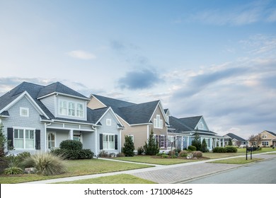 A street view of a new construction neighborhood with larger landscaped homes and houses with yards and sidewalks taken near sunset with copy space