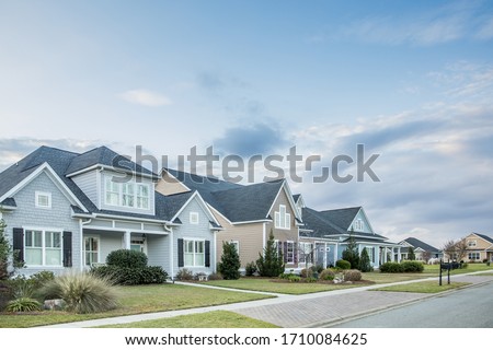 A street view of a new construction neighborhood with larger landscaped homes and houses with yards and sidewalks taken near sunset with copy space
