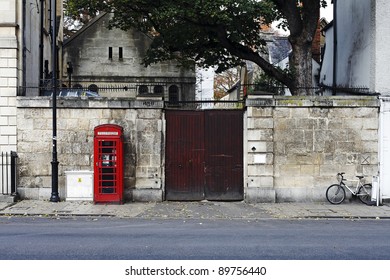 Street view of Oxford town, England, with an iconic red telephone box and bicycle parked against a vintage wall. - Powered by Shutterstock