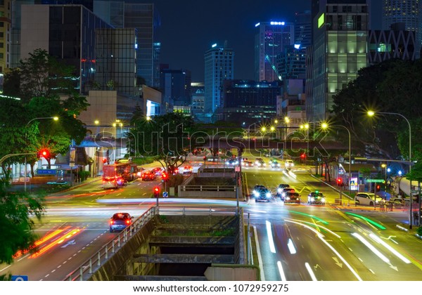 Street view of Singapore at night.\
Light trails at busy road with deep blue sky at\
background