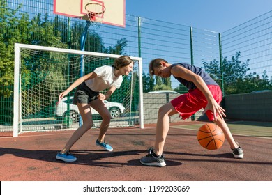 Streetball basketball game with two players, teenagers girl and boy, day on basketball court. - Powered by Shutterstock