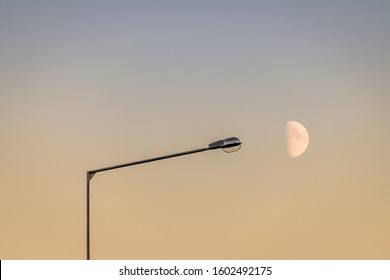 Streetlamp and a first quarter moon against an evening sky