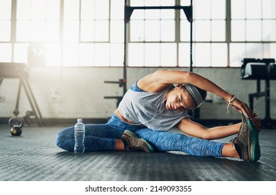 Strength Is Her Middle Name. Shot Of A Young Attractive Woman Stretching In A Gym.