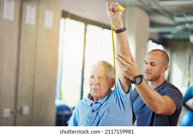 Strength never gets old. Shot of a senior man working out with the help of a trainer.
