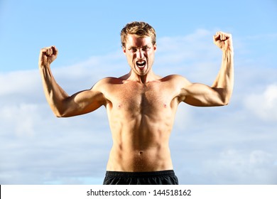 Strength - Strong Aggressive Fitness Man Flexing Muscles Showing Power Pose Outside. Muscular Fit Male Fitness Man Celebrating Success Macho Style.