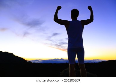 Strength - strong success fitness man flexing muscles showing power pose outside in silhouette at night. Muscular fit male fitness man celebrating success macho style. - Powered by Shutterstock