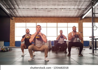 Strength Training In Gym. Small Group Of Muscular Male Adults Training Squats With Weights. Teamwork, Sports And Fitness