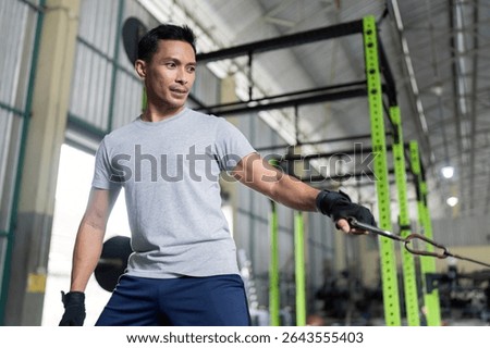 Strength Training. Man performing cable exercise at gym for upper body workout.