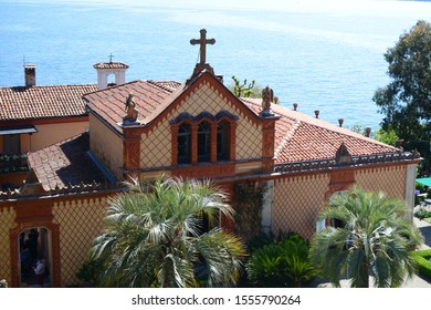 Stresa, Italy - 01 May 2019 Borromeo House, Details Of The Facade Family Chapel, With Beautiful Decorations Made With Terracotta Panels. On The Background The Lake Maggiore.