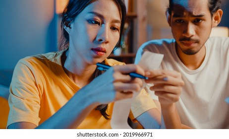 Stress asia couple man and woman use calculator for calculate family budget, debts, expenses during financial economic crisis at home at night. Marriage money trouble, Family budget plan concept. - Powered by Shutterstock