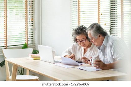 Stress Asian Senior Couple using calculator and calculate family budget, Debts, monthly expenses in home during Financial economic crisis. Elderly man, woman looking at bill, passbook, receipt, laptop