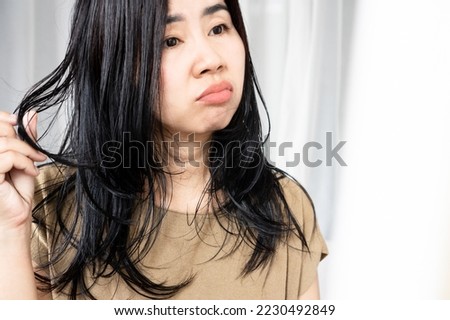 stress Asian woman have problems with oily hair and thinning hair looking at the mirror 