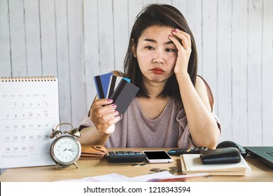 Stress Asian Woman Looking At Credit Cards In Hand No Money For Debt With Deadline Calendar On Desk 