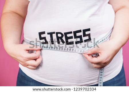 stress, eating problems, compulsive overeating, weight gain. overweight woman with big belly and measuring tape, close up