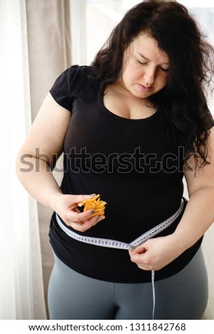 stress, eating problems, compulsive overeating, fat food, weight gain. overweight woman with potato chips and measuring tape on her waist