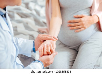 Stress is forbidden. Scaled up look on a doctor holding hand of a pregnant woman while checking her pulse during a monthly check up. - Powered by Shutterstock