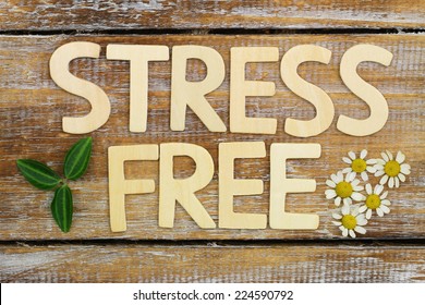 Stress free written with wooden letters on rustic wooden surface with fresh chamomile flowers 