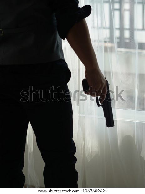 Stress\
man holding gun on hand . Robber or gangster,thief holding gun in\
hand. Man holding a gun in his hand ready to\
shoot