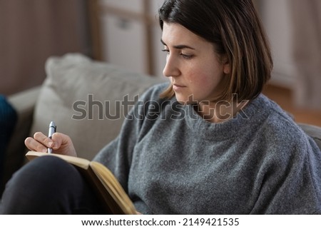 stress, mental health and depression concept - sad crying woman with diary sitting on sofa at home