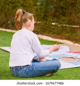 Stress Relief With Art Therapy. Back View Teenager Girl Paints A Paper House Template With Colorful Watercolors On The Grass In The Garden. Homeschool, Child Play Outdoor Play-area On Tne Backyard.