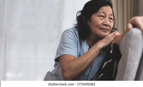 Stress And Thinking Asian Elderly Woman Is Lonely Sitting On The Sofa Near The Window, Concept Of Mental And Healthcare Of Older People In Family.