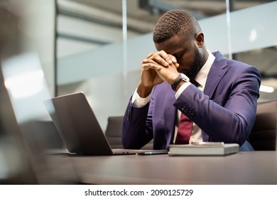 Stressed african american young businessman in suit having burnout, sitting in his office in front of laptop, leaning on his hands, suffering from financial crisis during COVID-19 pandemic, copy space - Powered by Shutterstock