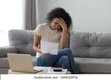 Stressed African Woman Holding Papers Calculate Domestic Bills At Home Worried About Bankruptcy Financial Problem Bank Debt, Depressed Sad Black Lady Frustrated About Lack Of Finances Sit On Sofa