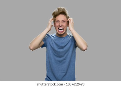 Stressed Angry Teenage Boy. Emotional Portrait Of Furious Teenager Screaming With Anger Against Gray Background. Full Of Rage. Symptoms Of Nervous Breakdown.