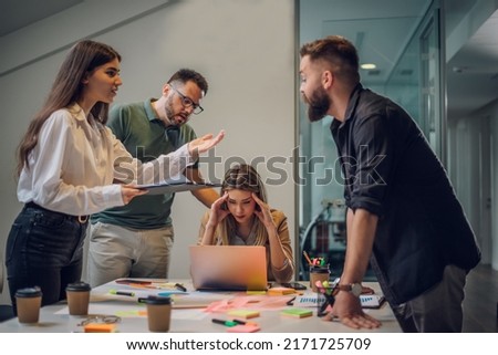 Stressed annoyed office employee manager having headache migraine at business meeting with his colleagues about business problem they have to solve. Stress at work or migraine concept.