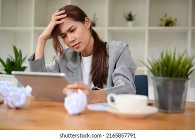 Stressed Asian businesswoman unsatisfied with her work, using portable tablet to check her email, receiving a bad email from her boss, getting a complained from customer.