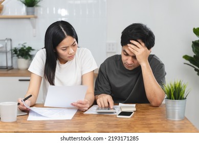 Stressed Asian couple looking at financial debt notice papers from bank. - Shutterstock ID 2193171285
