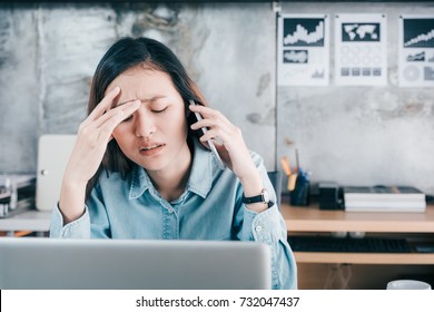 Stressed Asian Creative Designer Woman Cover Her Face With Hand And Feel Upset While Talk On Mobile Phone With Customer In Front Of Laptop Computer On Desk At Office,Stress Office Lifestyle Concept.