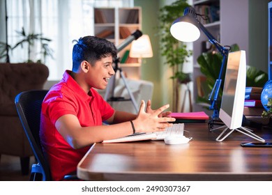 Stressed Asian Indian Teenage School Boy Learning Virtually at Home, Showing Stress and Anxiety While Using Computer, Headphones, and Smartphone for Online Classes, Isolated on White Background - Powered by Shutterstock